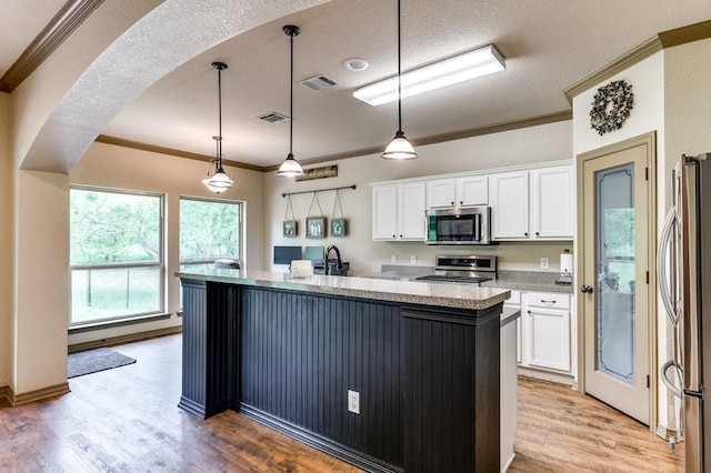 870 1st St, Maypearl, TX 76064 - kitchen featuring stainless steel appliances, ornamental molding, white cabinets, light wood-style floors, and an island with sink