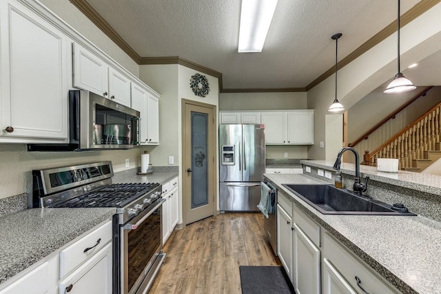 870 1st St, Maypearl, TX 76064 - kitchen featuring appliances with stainless steel finishes, a sink, crown molding, a textured ceiling, and light wood-style flooring