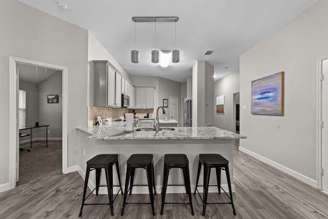 4719 Highlands Dr, Mckinney, TX 75070 - kitchen with a sink, stainless steel appliances, a peninsula, wood finished floors, and baseboards