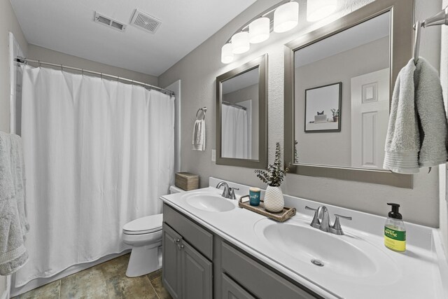 4719 Highlands Dr, Mckinney, TX 75070 - bathroom featuring double vanity, toilet, stone finish flooring, and curtained shower