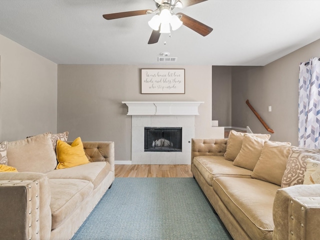 living area featuring wood finished floors, ceiling fan, and a fireplace