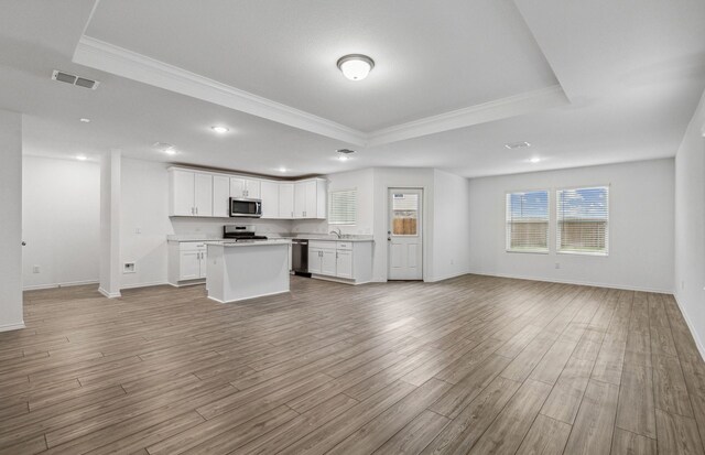 kitchen featuring stainless steel appliances, a tray ceiling, open floor plan, crown molding, and a kitchen island