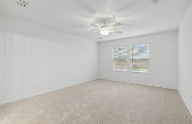 carpeted empty room featuring a smoke detector, a ceiling fan, and baseboards