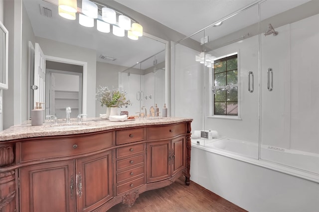 bathroom featuring wood finished floors, an enclosed shower, a bath, and double vanity
