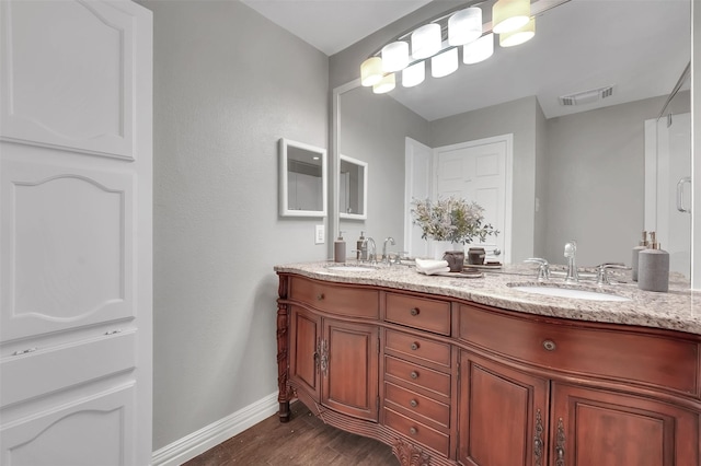 full bathroom featuring wood finished floors, baseboards, and double vanity