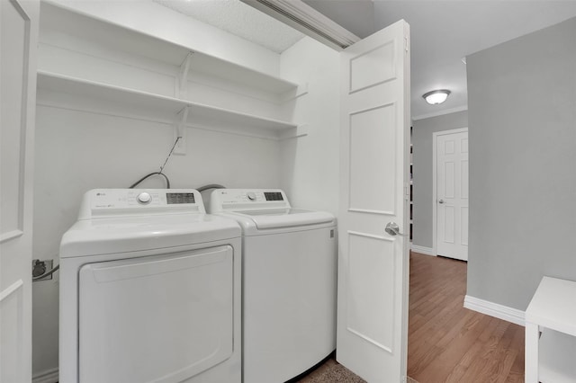 clothes washing area featuring independent washer and dryer, wood finished floors, ornamental molding, and baseboards