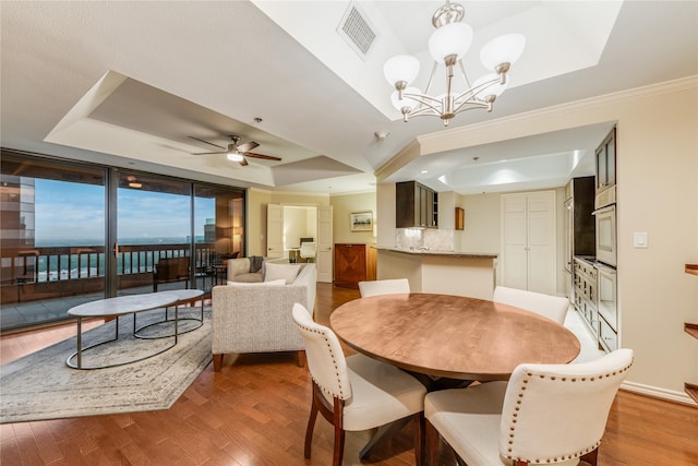 5909 Luther Ln Unit 1700, Dallas, TX 75225 - dining space featuring a raised ceiling, wood finished floors, ceiling fan, a chandelier, and ornamental molding