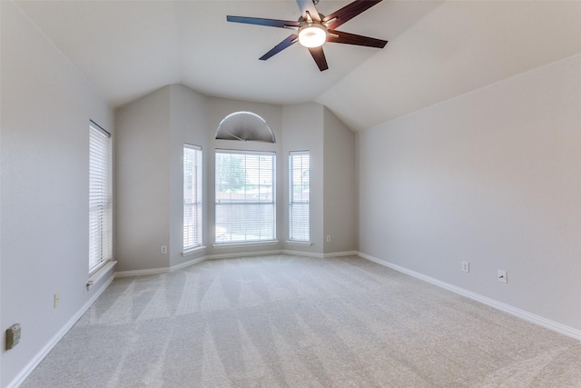 empty room featuring light carpet, a ceiling fan, vaulted ceiling, and baseboards