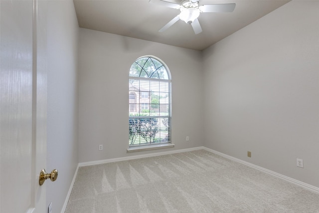 carpeted spare room with baseboards and a ceiling fan