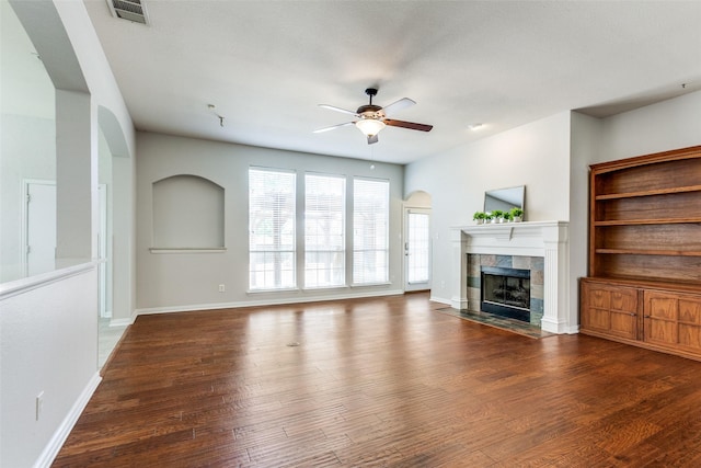 unfurnished living room featuring ceiling fan, a tile fireplace, wood finished floors, and baseboards