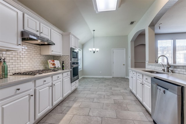 kitchen with appliances with stainless steel finishes, a sink, under cabinet range hood, decorative backsplash, and light countertops