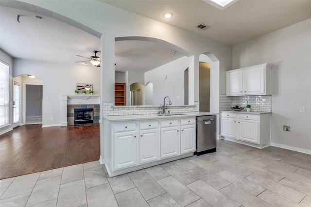 kitchen with stainless steel dishwasher, a sink, a ceiling fan, light countertops, and backsplash