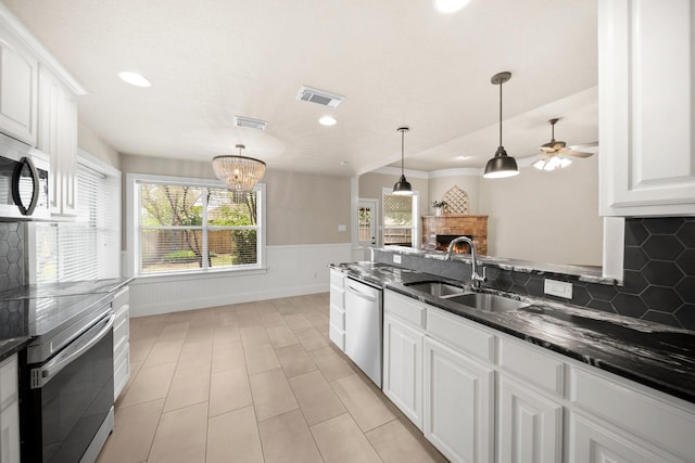 816 Ridgecrest Ct, Aubrey, TX 76227 - kitchen featuring a sink, stainless steel appliances, wainscoting, white cabinets, and dark stone countertops
