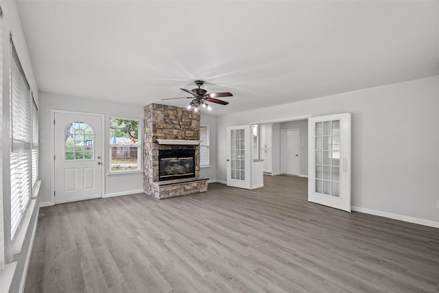 2001 Brenda Ave, Denison, TX 75020 - unfurnished living room featuring french doors, a ceiling fan, wood finished floors, a stone fireplace, and baseboards