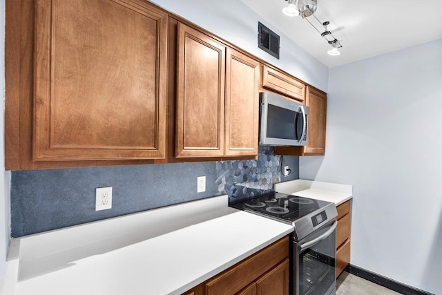 3103 Wycliff Ave, Dallas, TX 75219 - kitchen with appliances with stainless steel finishes, light countertops, brown cabinetry, and track lighting
