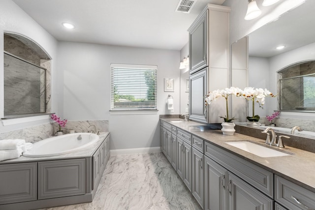 full bath with a garden tub, tiled shower, double vanity, marble finish floors, and baseboards