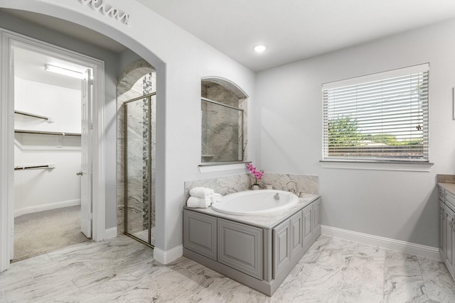 full bath with marble look tiles, a stall shower, a bath, and a spacious closet