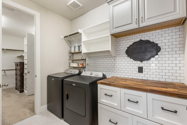 washroom with separate washer and dryer, cabinet space, light carpet, light tile patterned floors, and baseboards