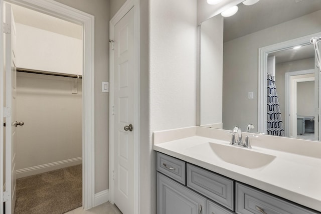 bathroom featuring vanity, baseboards, and a walk in closet