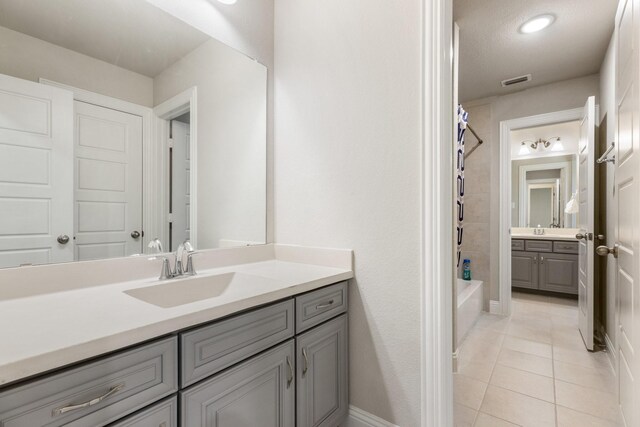 full bath featuring tile patterned flooring, two vanities, shower / bath combo, and baseboards