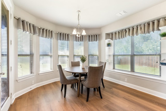 dining area with a chandelier, baseboards, wood finished floors, and plenty of natural light