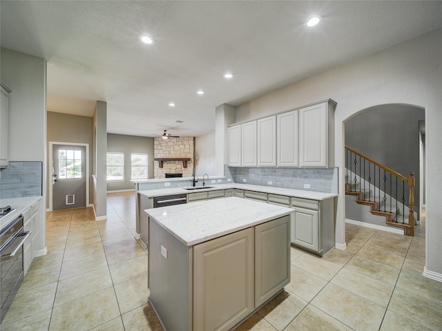 kitchen featuring decorative backsplash, a peninsula, a sink, a fireplace, and recessed lighting