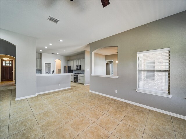 unfurnished living room featuring arched walkways, light tile patterned floors, plenty of natural light, recessed lighting, and ceiling fan