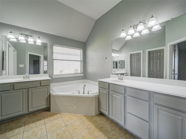 bathroom with vaulted ceiling, tile patterned floors, a garden tub, and two vanities