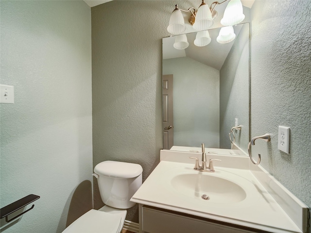 bathroom featuring toilet, vanity, and a textured wall