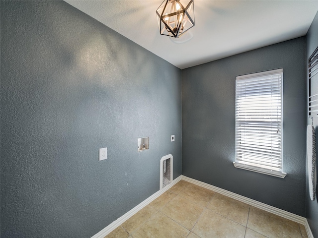 washroom featuring electric dryer hookup, light tile patterned floors, hookup for a washing machine, baseboards, and a textured wall