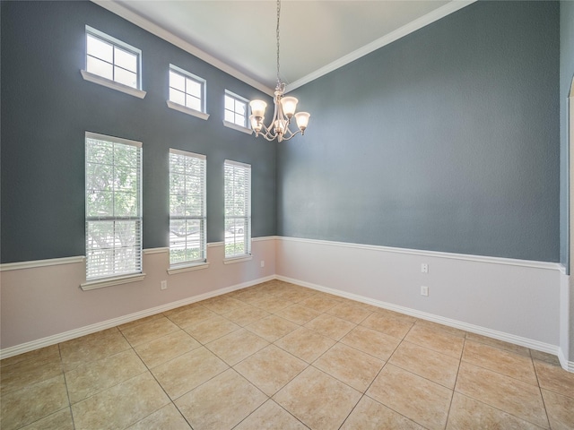 empty room with tile patterned flooring, a chandelier, baseboards, and crown molding
