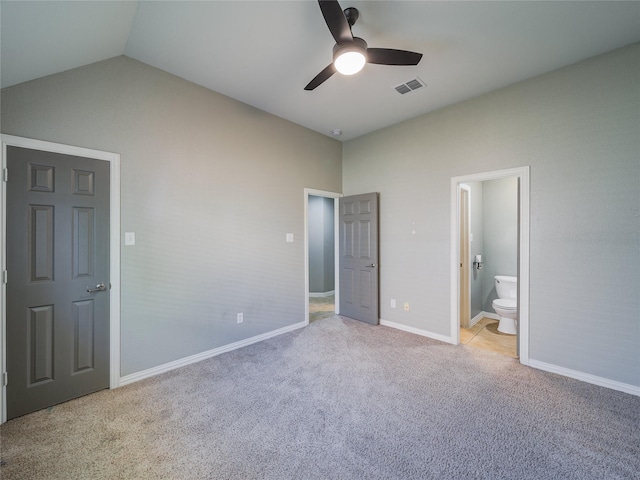 unfurnished bedroom featuring lofted ceiling, carpet, baseboards, ensuite bathroom, and a ceiling fan
