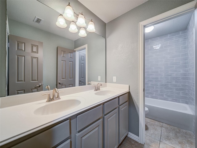 bathroom with toilet, double vanity, tile patterned flooring, a textured wall, and shower / tub combination