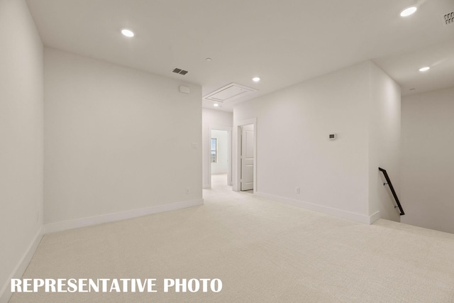 empty room with attic access, recessed lighting, light colored carpet, and baseboards