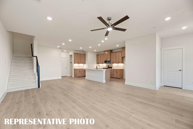 unfurnished living room with a ceiling fan, baseboards, a sink, recessed lighting, and light wood-style flooring
