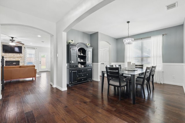 3200 Hawks View Ln, Denton, TX 76208 - dining space featuring arched walkways, a ceiling fan, dark wood-style flooring, a chandelier, and a stone fireplace