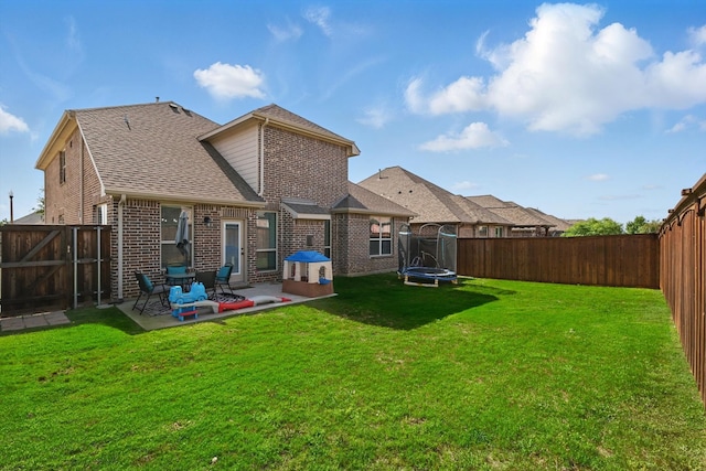 3200 Hawks View Ln, Denton, TX 76208 - rear view of property with a trampoline, a patio, brick siding, and a fenced backyard