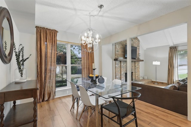 1738 Northaven Ct, Arlington, TX 76012 - dining room featuring light wood-style flooring, a brick fireplace, a chandelier, and a textured ceiling