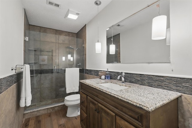 1738 Northaven Ct, Arlington, TX 76012 - bathroom with tile walls, a stall shower, toilet, wood finished floors, and vanity