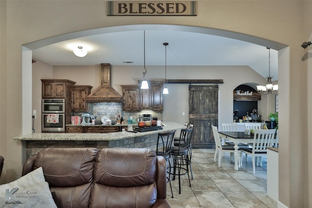 3726 Enchanted Rock Rd, Abilene, TX 79606 - kitchen with premium range hood, decorative backsplash, stainless steel double oven, arched walkways, and a chandelier