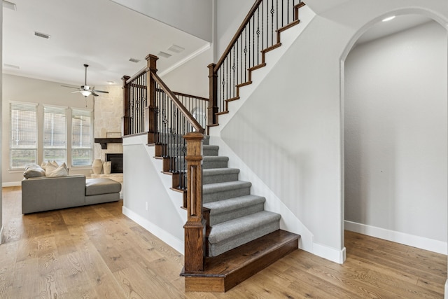 2831 Sheffield Ct, Trophy Club, TX 76262 - stairway featuring a ceiling fan, a stone fireplace, arched walkways, wood finished floors, and baseboards