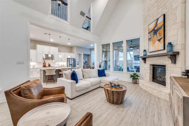 771 Drummond Dr, Prosper, TX 75078 - living area with light wood-style floors, a towering ceiling, a stone fireplace, baseboards, and a ceiling fan