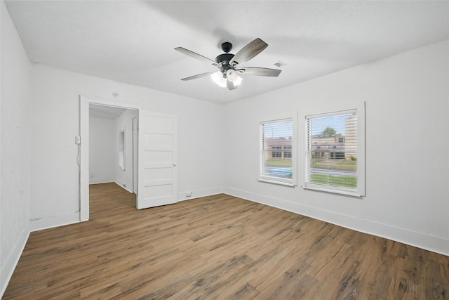 empty room with wood finished floors, ceiling fan, and baseboards