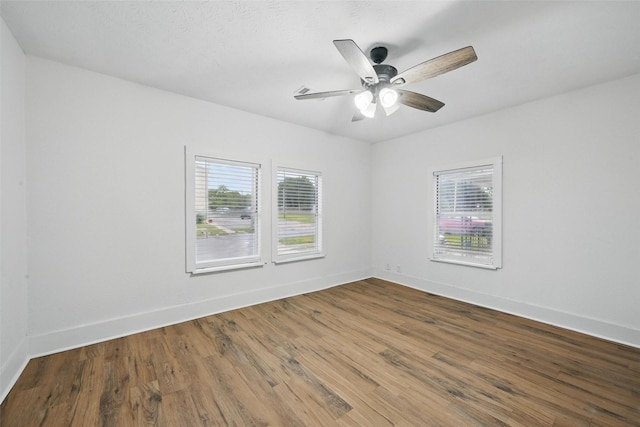 unfurnished room featuring healthy amount of natural light, wood finished floors, baseboards, and a ceiling fan
