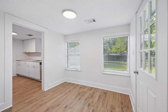 unfurnished dining area with light wood finished floors and baseboards
