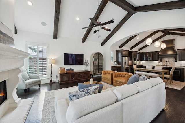 870 Swan Landing Ln, Allen, TX 75013 - living area with arched walkways, a warm lit fireplace, ceiling fan, beam ceiling, and dark wood-type flooring
