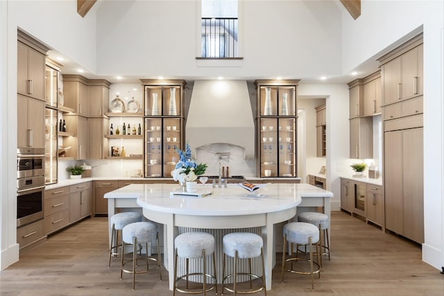 2300 Sorrelwood Ct, Celina, TX 75009 - kitchen with high vaulted ceiling, custom exhaust hood, tasteful backsplash, a large island with sink, and light wood-style flooring