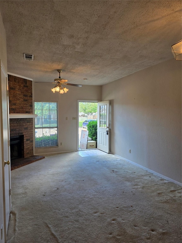 3801 14th St Unit 1004, Plano, TX 75074 - unfurnished living room with a textured ceiling, baseboards, carpet floors, a fireplace, and a ceiling fan