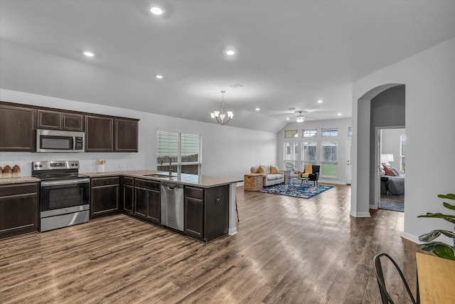 kitchen featuring stainless steel appliances, a sink, arched walkways, dark brown cabinetry, and a ceiling fan
