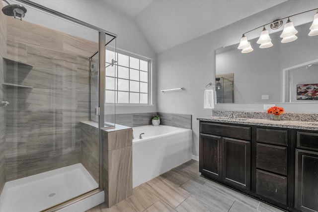 bathroom with a stall shower, vanity, a bath, and lofted ceiling
